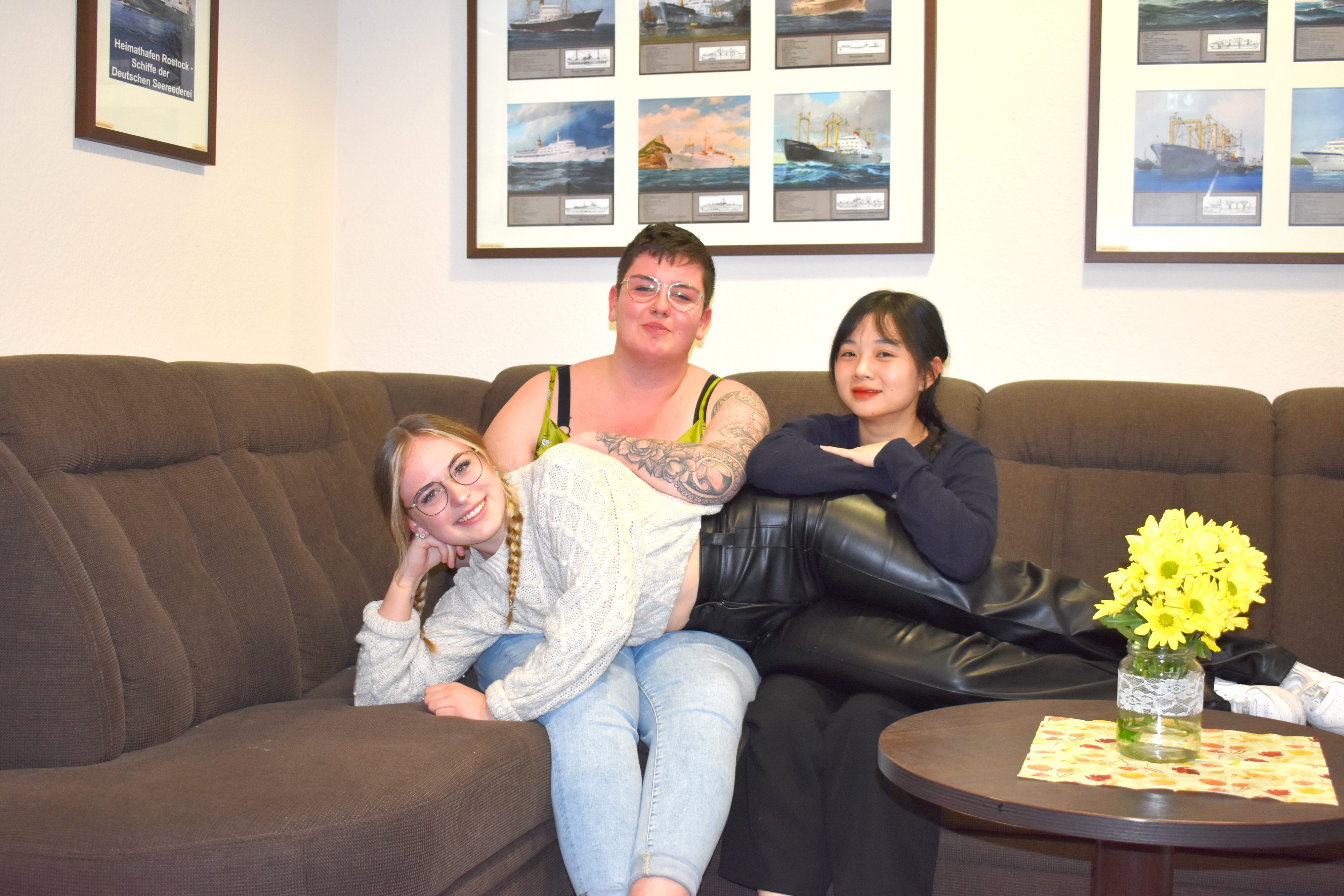 Drei weibliche Azubis, zwei sitzen auf der Couch, eine liegt quer auf deren Schoß